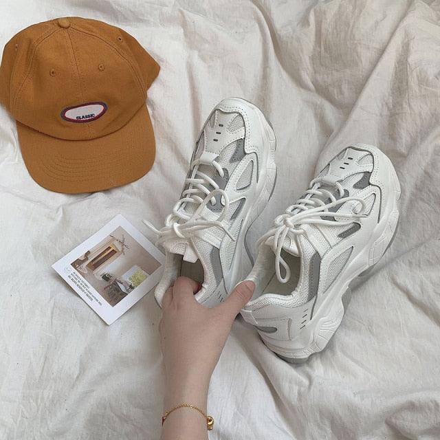 Pair white mesh chunky sneakers with thick sole and lace-up design beside an orange cap on Tampa Home & Garden Store