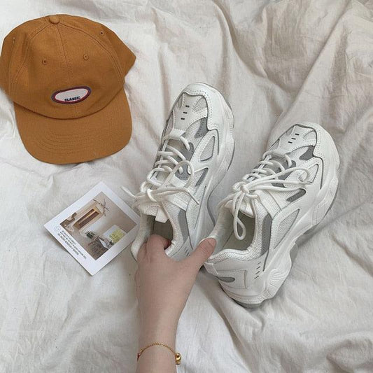 Pair white mesh chunky sneakers with thick sole and lace-up design beside an orange cap on Tampa Home & Garden Store