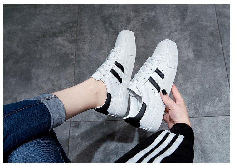 Women's white casual sneakers pair with black stripes, lace-up vulcanized style on Tampa Home & Garden Store
