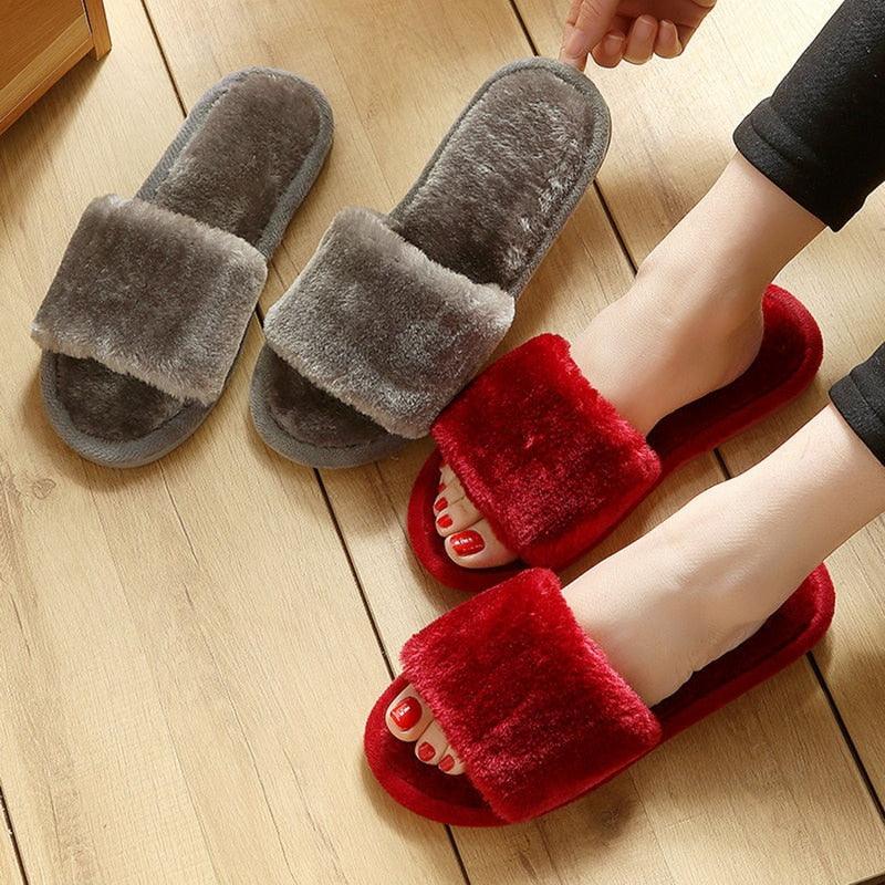 Stevvex slippers: two gray plush indoor slippers and one red plush fur slide on wooden floor on Tampa Home & Garden Store