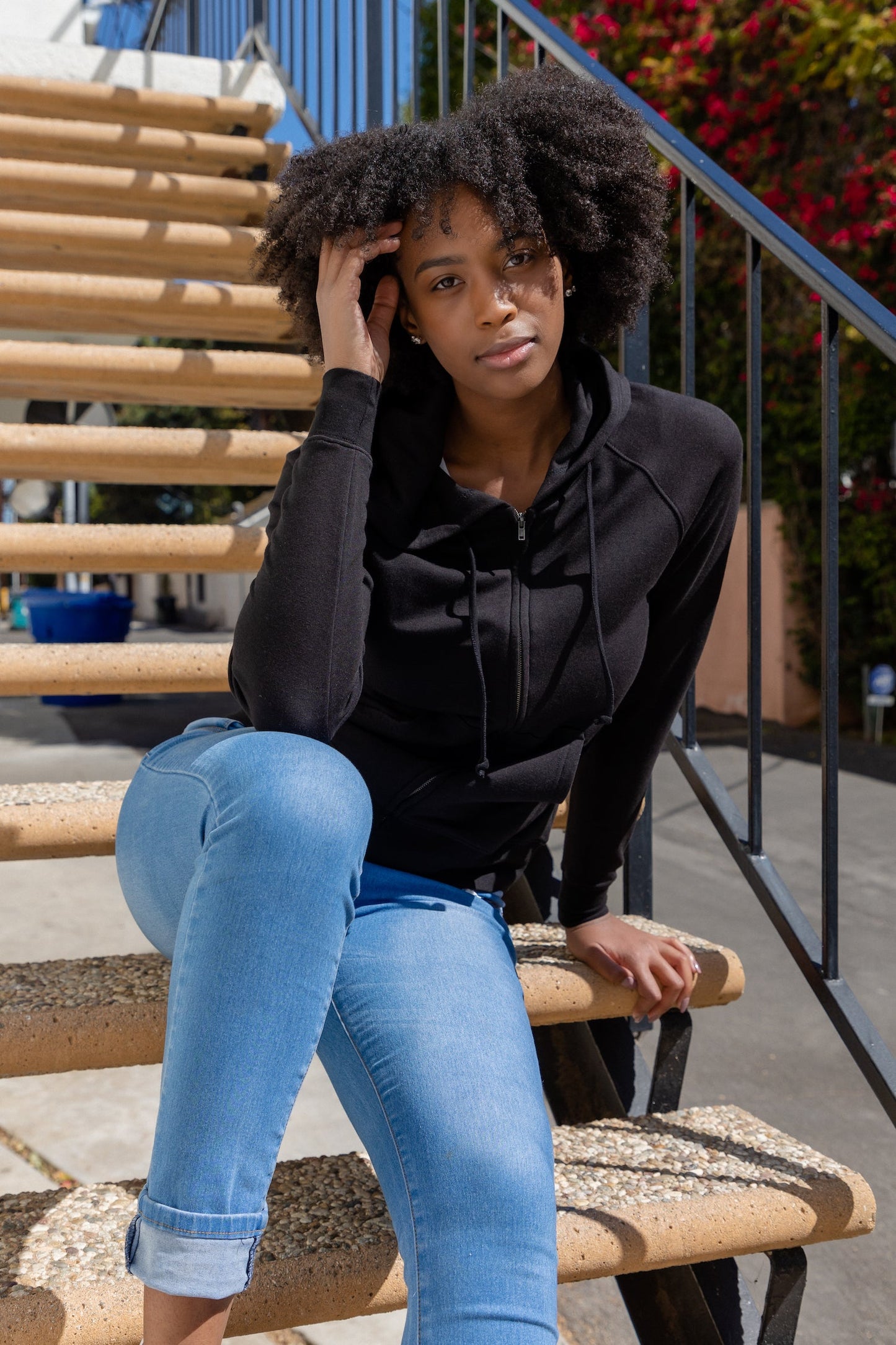Women's Spun Bamboo zip hoodie in black, bamboo French Terry, worn by model on outdoor stairs on Tampa Home & Garden Store