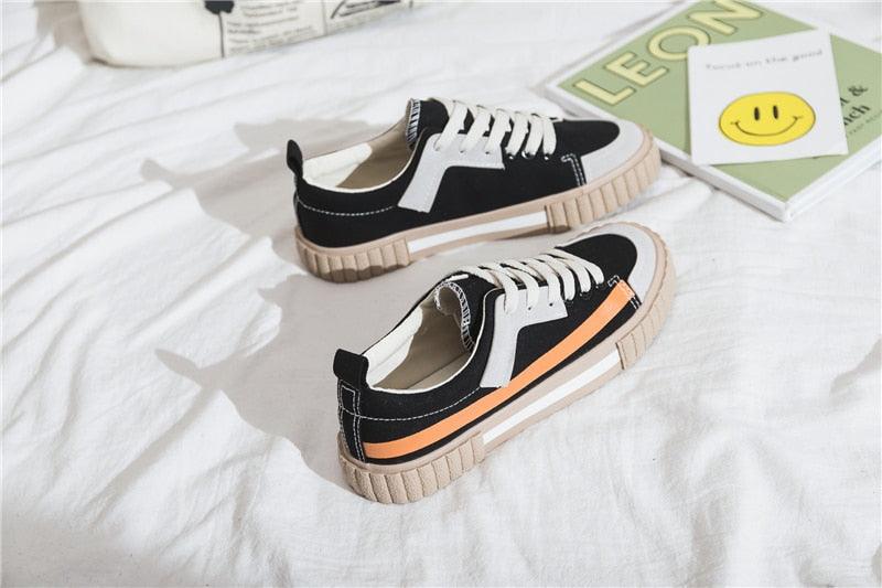 Womens canvas sneakers pair in black with white laces, beige sole and orange stripe accent on Tampa Home & Garden Store