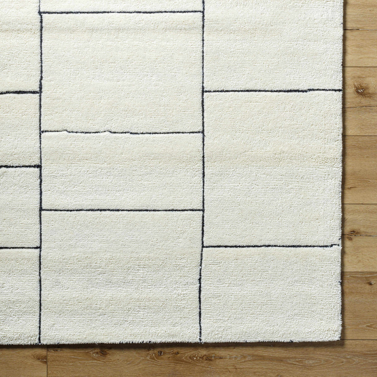 Xylia Ivory Area Rug by Boutique Rugs with cream color and black grid pattern on wood floor on Tampa Home & Garden Store