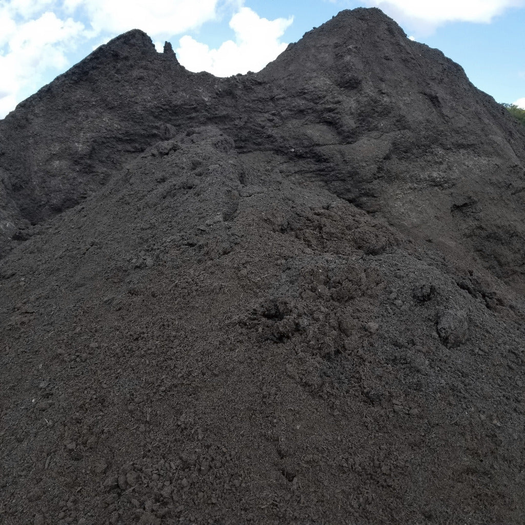 Pile of manure compost for sale delivered bulk shown wet by rain.